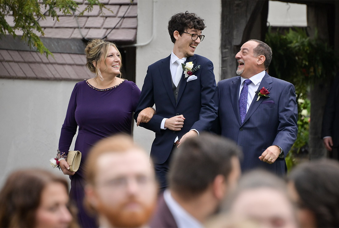 The groom laughing with his parents as they walk him down the aisle at the Bull Estate at Addison Oaks in Leonard, Michigan.