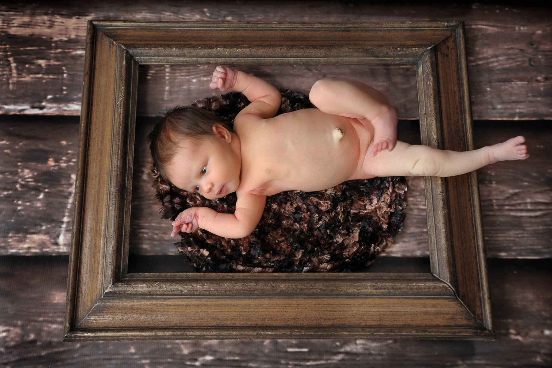 Best Detroit newborn photographer of a baby in a frame doing a pose much like the ceiling of the Sistine Chapel, except this is in metro Detroit, Michigan at my studio.
