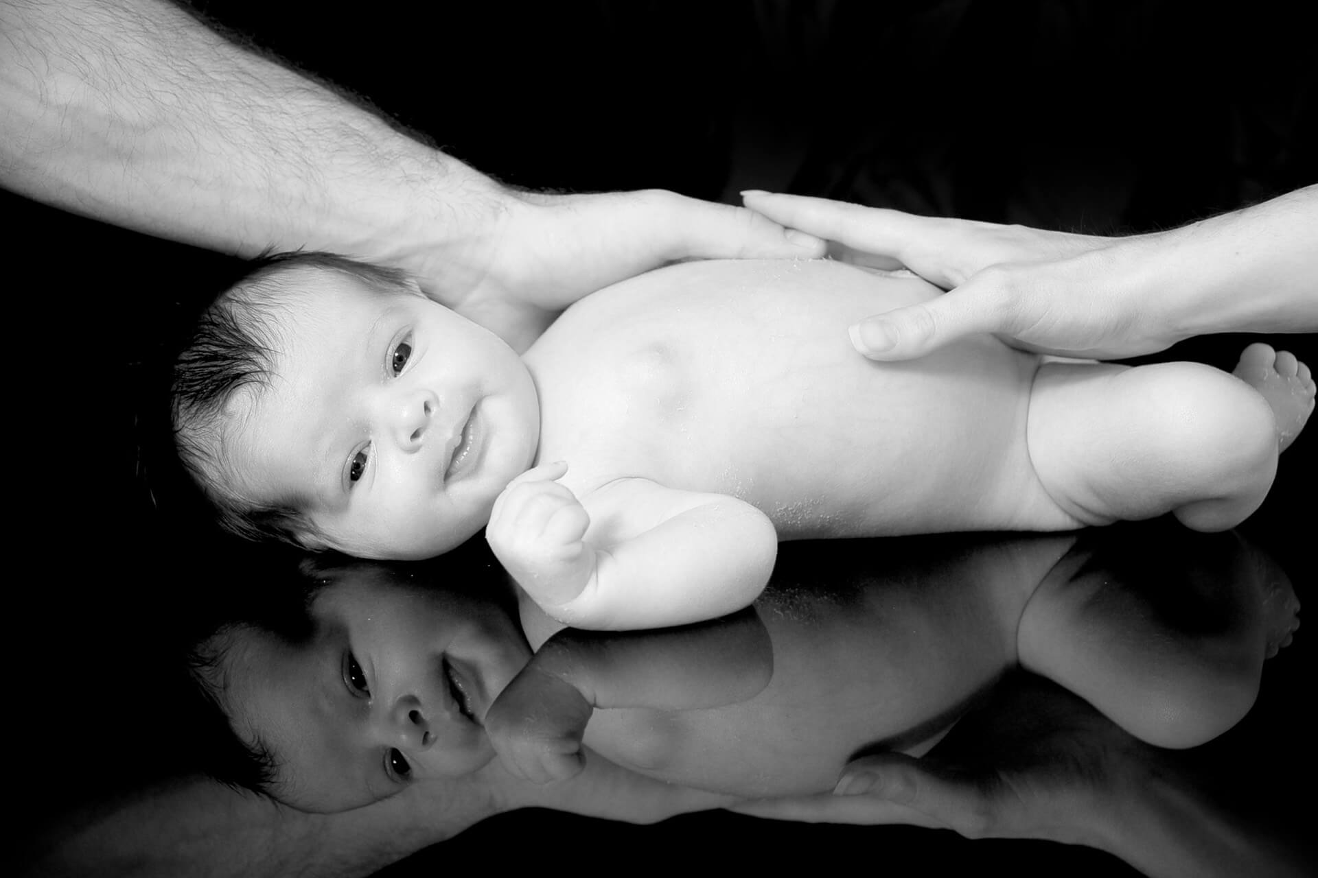 Best Detroit baby photographer takes candid newborn photos with the baby's parents is reflected during this infant photography session in metro Detroit, Michigan.