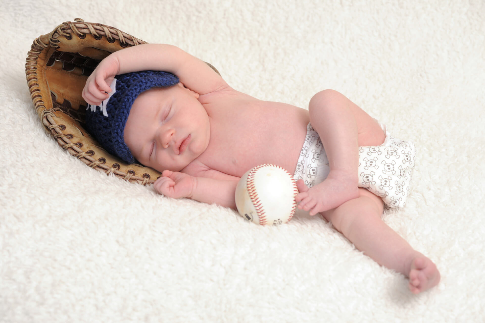 Best Detroit baby photographer's fun and candid infant photos of a baby seemingly pitching and showing off his best Detroit Tiger form during his Detroit, Michigan baby session.