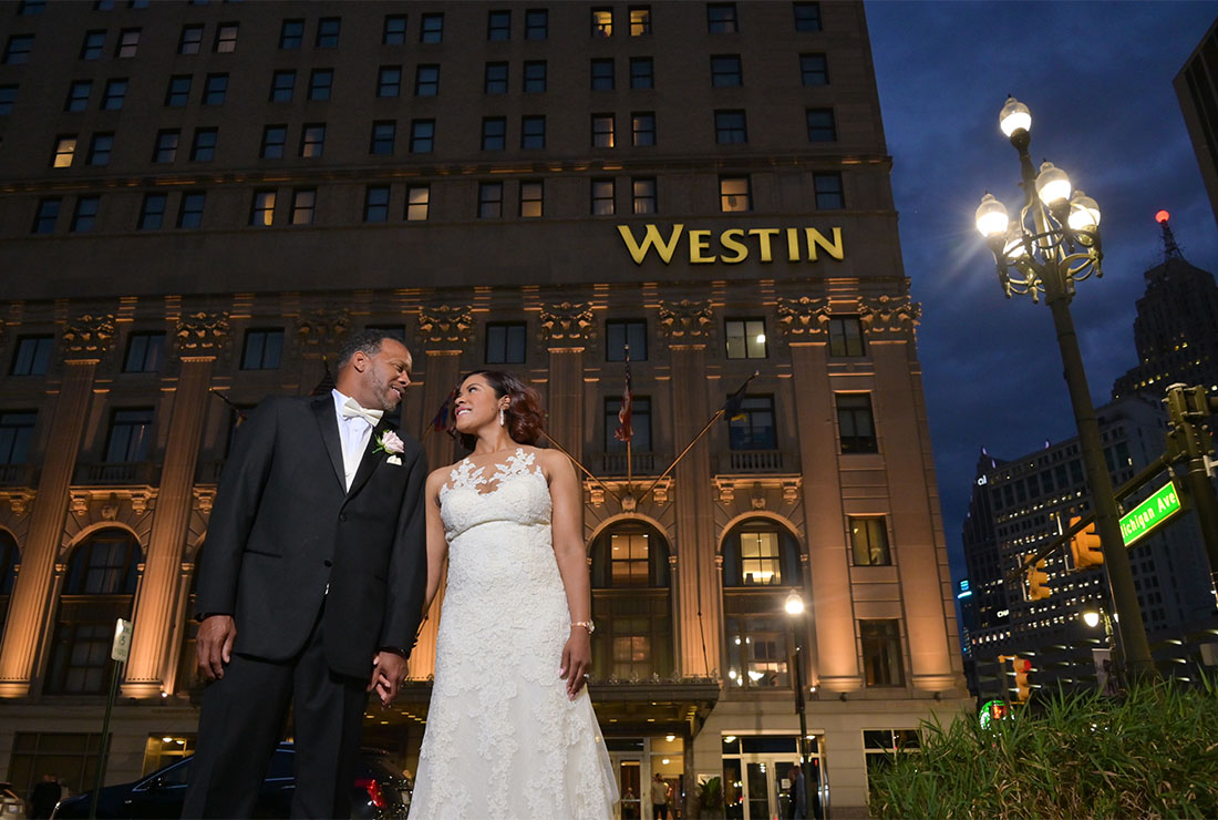 The groom and bride outside their wedding venue at the Book Cadillac Hotel in Detroit, Michigan.