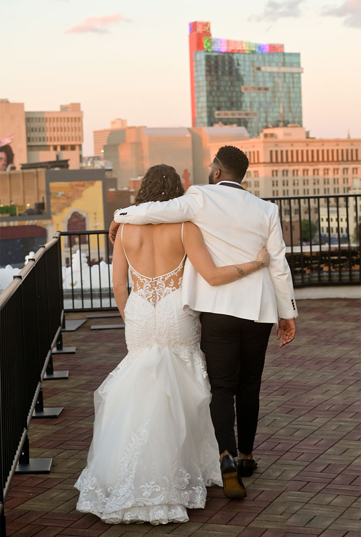 The groom and bride on top of their venue at golden hour at the Detroit Opera House in Detroit, Michigan.