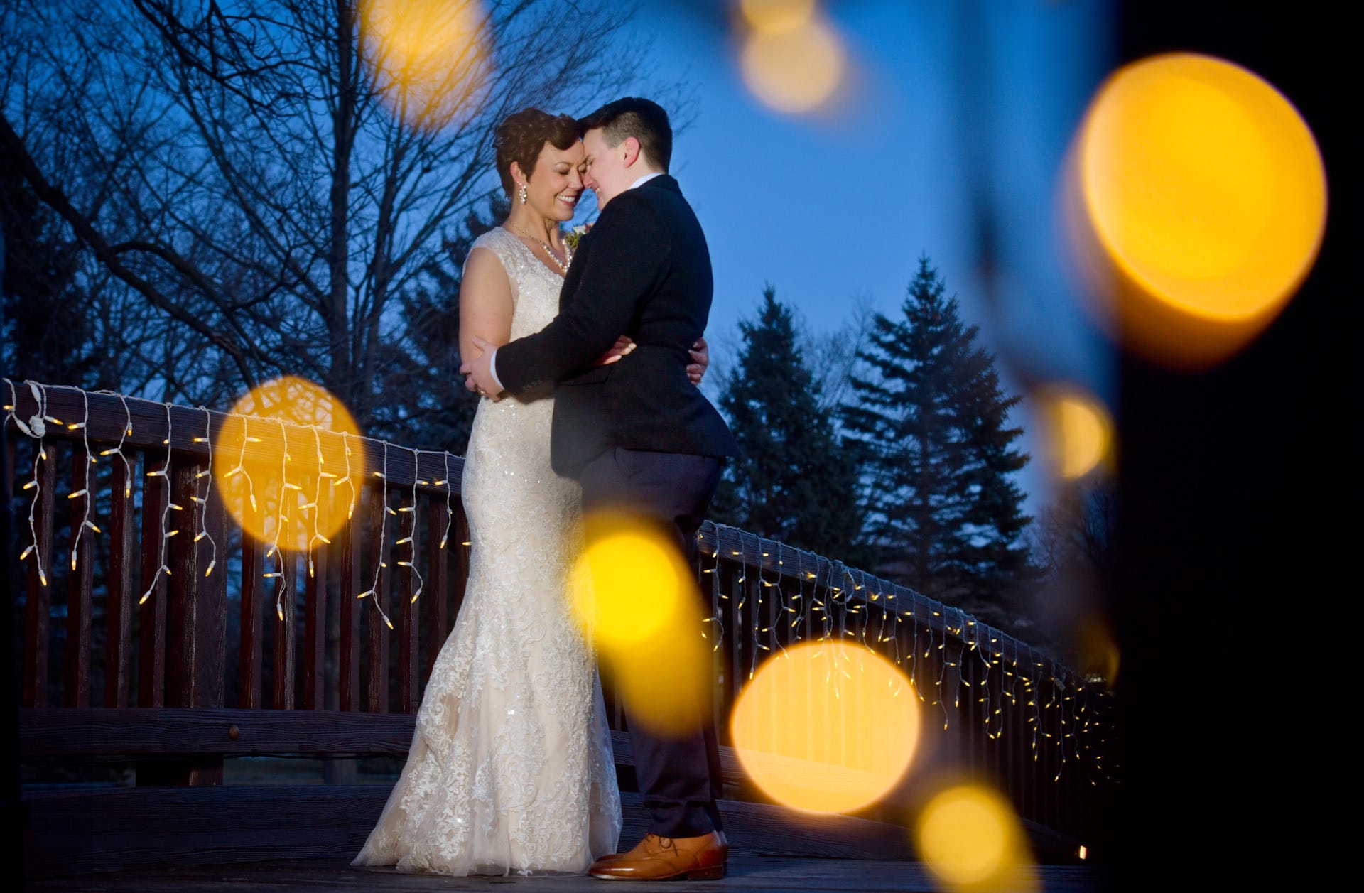 A same sex couple dance on the bridge of their family home at dusk in winter in Troy, Michigan.