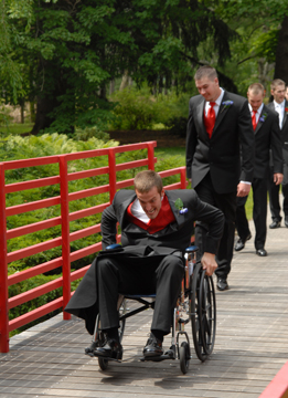 The best man goofs around in a wheelchair after the wedding ceremony.