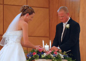 Groom jams the candle back into place after the unity candle during Macomb county wedding