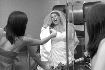 Warren MI bride laughs as she gets bustled in the bathroom.