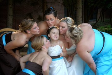 The bride and bridesmaids all give the flowergirl a kiss.