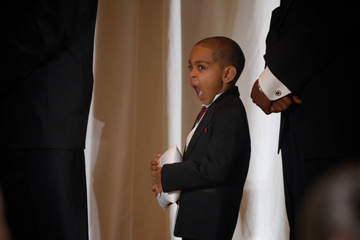 The ring bearer lets loose a yawn during the wedding ceremony in Redford, MI