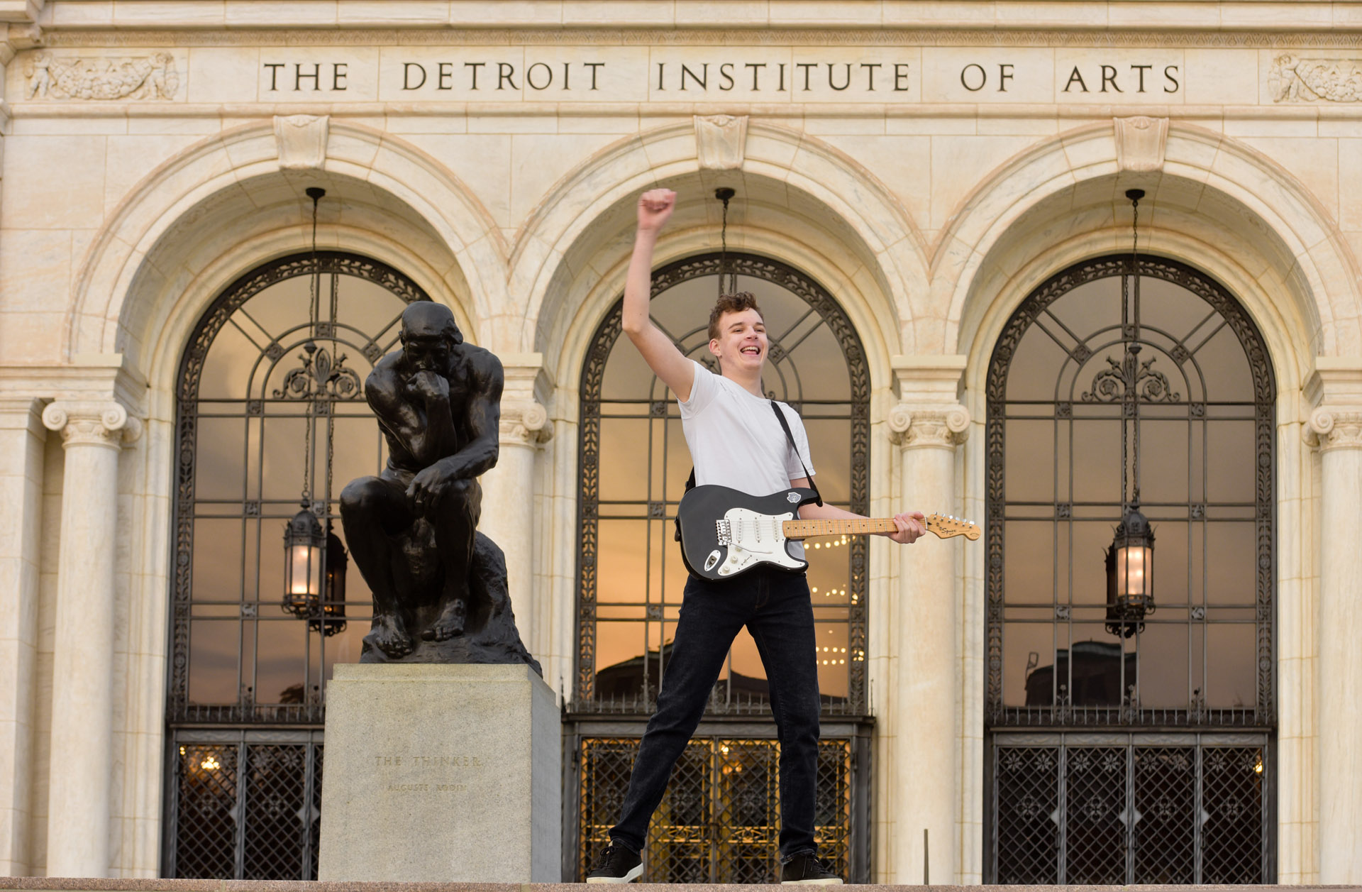 Super fun Detroit senior photo taken in front of the Detroit Institute of Art with a Troy High senior playing his guitar.