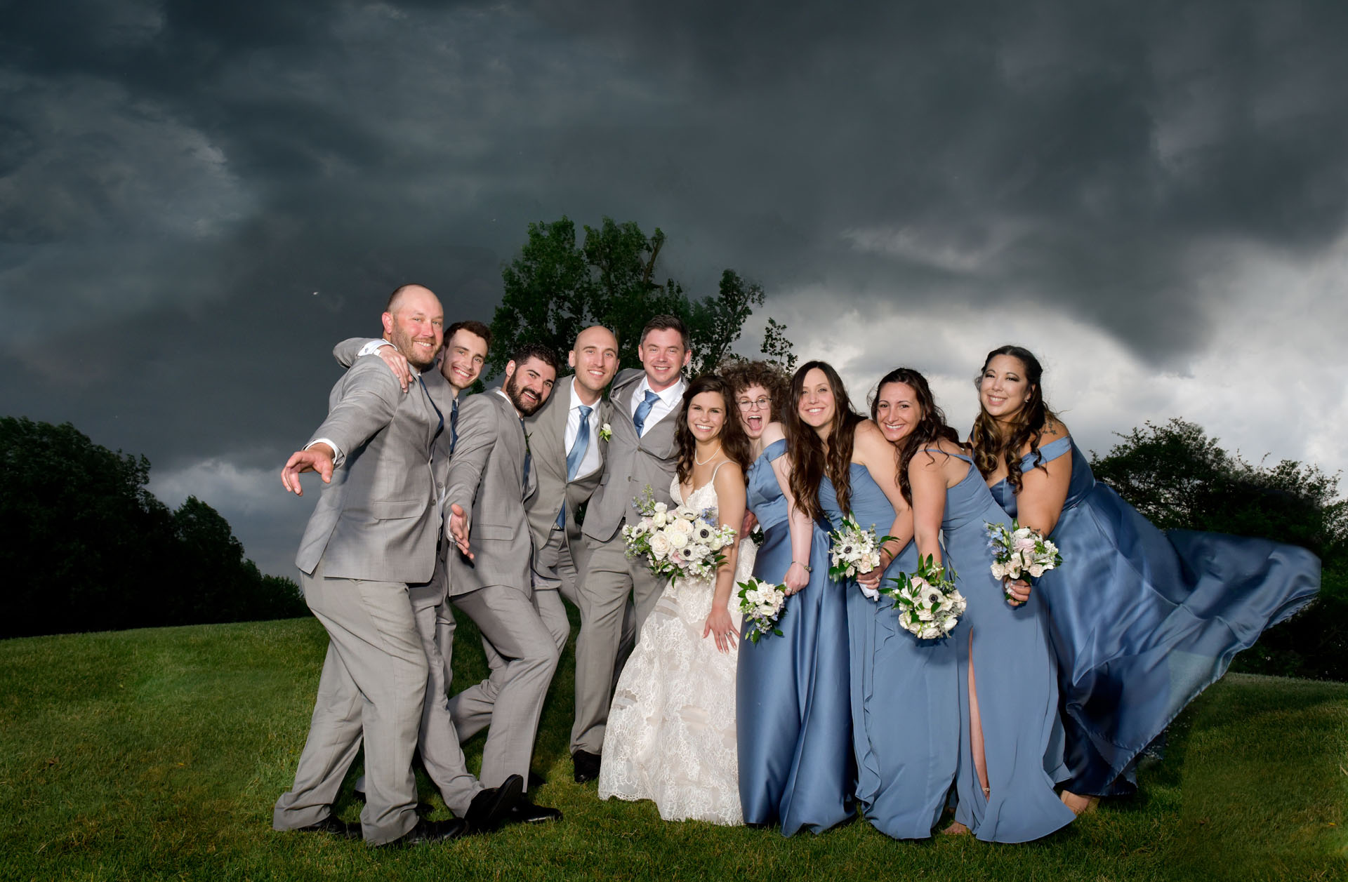 A wedding party climbs on top of hill at Ann Arbor's Stonebridge Golf Course just before a massive storm hits for this super full wedding party photo.