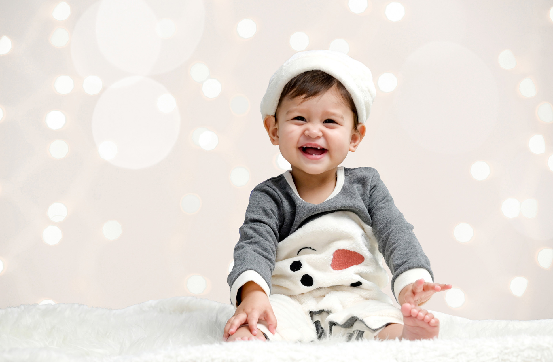Cutest baby in the world sits for a baby's first Christmas photo in her snowman outfit in Ann Arbor, Michigan.
