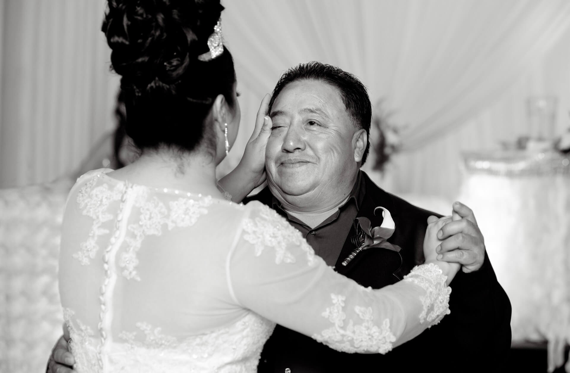Michigan wedding photographer takes photojournalists photos of a bride wiping a tear from her father's cheek during their father daughter dance in this Mexican wedding in Detroit, Michigan.