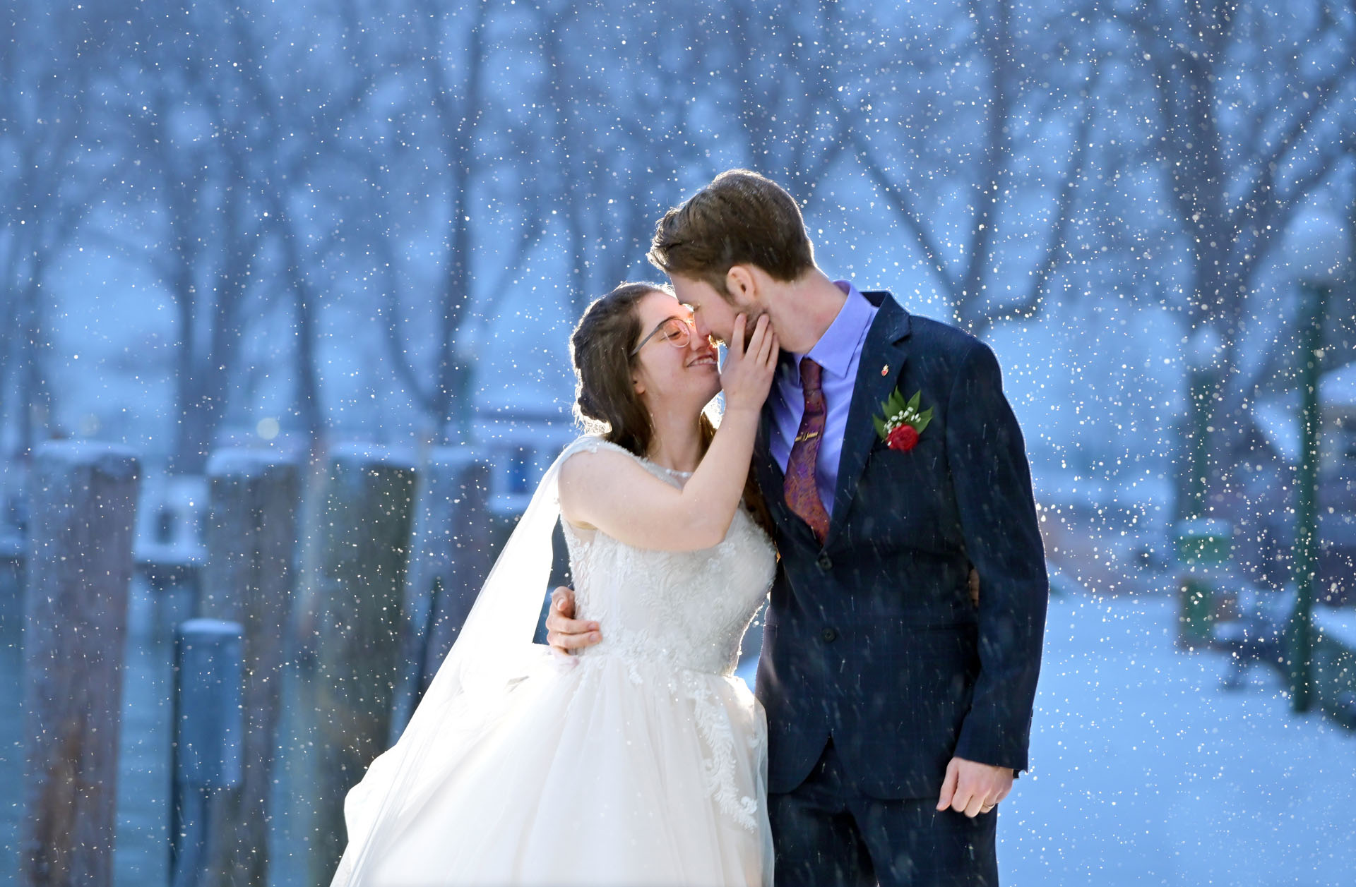 A winter wedding couple poses as it snows on their wedding day at the Detroit Yacht Club on Belle Isle in Detroit, Michigan.