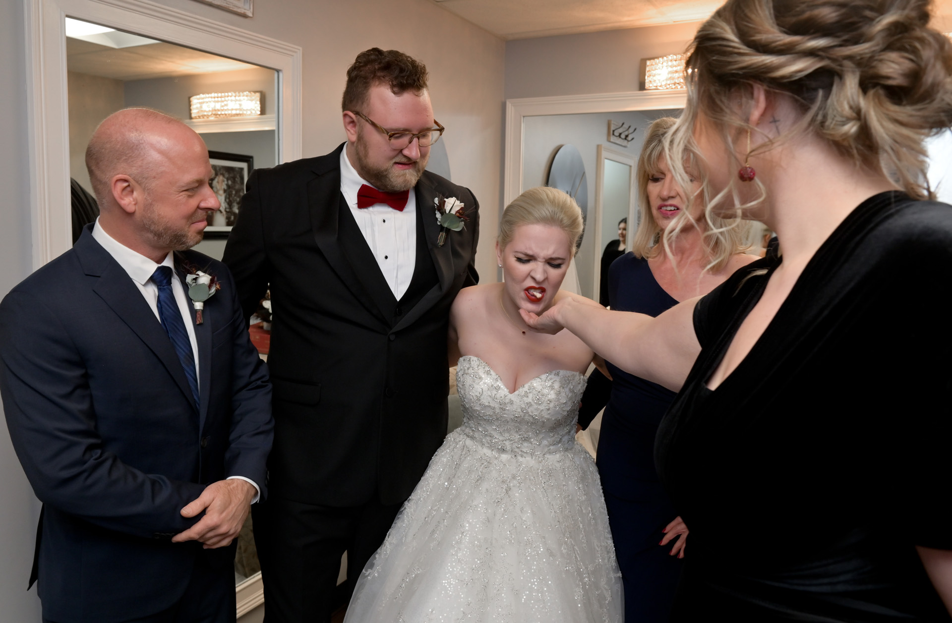 The bride spits out her gum into the maid of honor's hand during an impromptu family photo at a church in Macomb, Michigan.