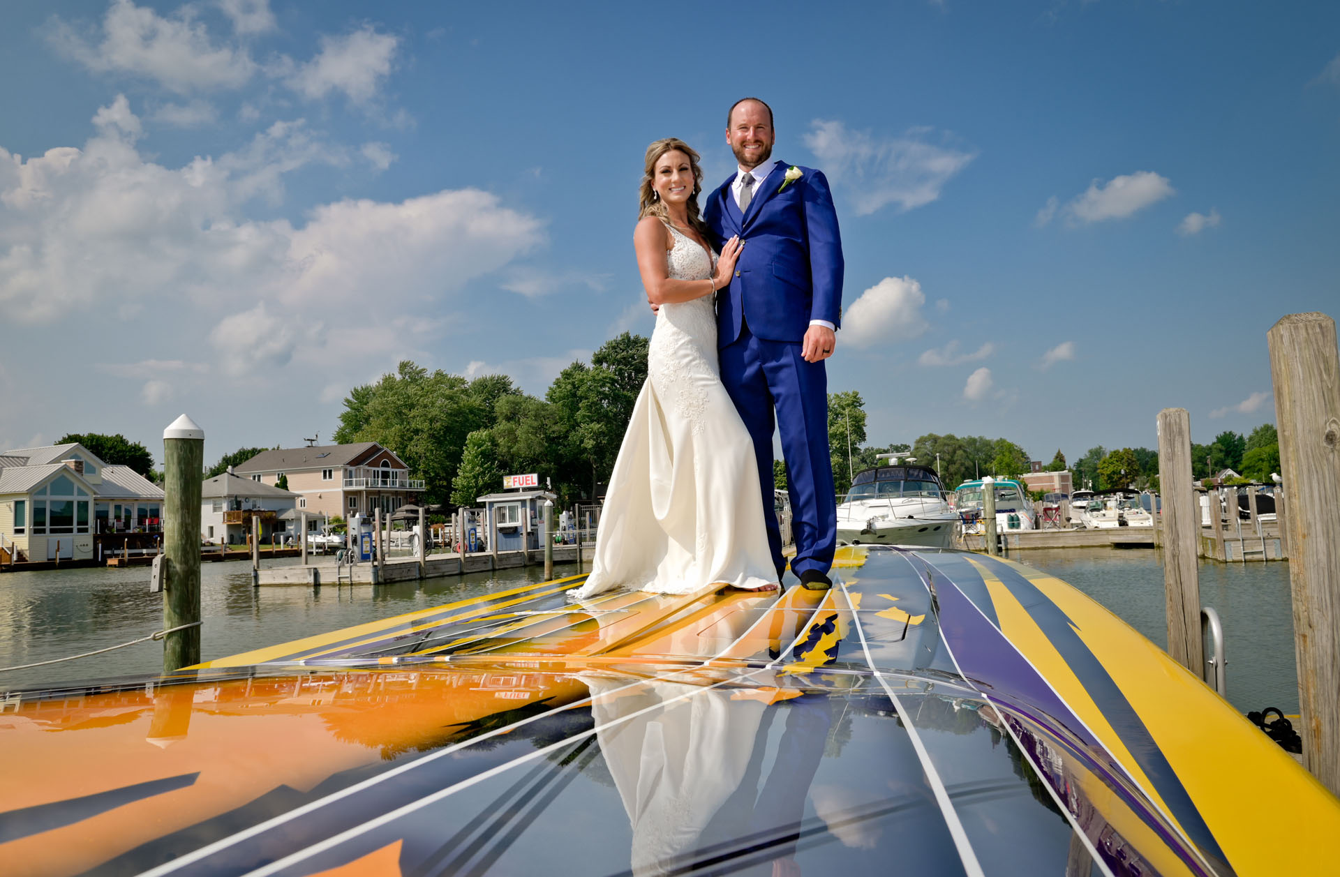 The bride and groom pose on his racing boat in St. Clair, Michigan at their docks during their wedding.
