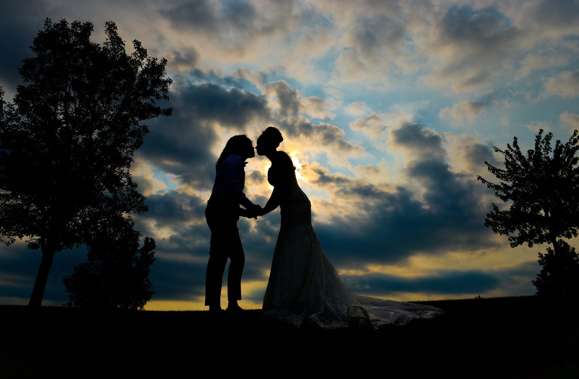 Two brides kiss in silhouette at the Fox Hills Golf Course in Plymouth, Michigan.