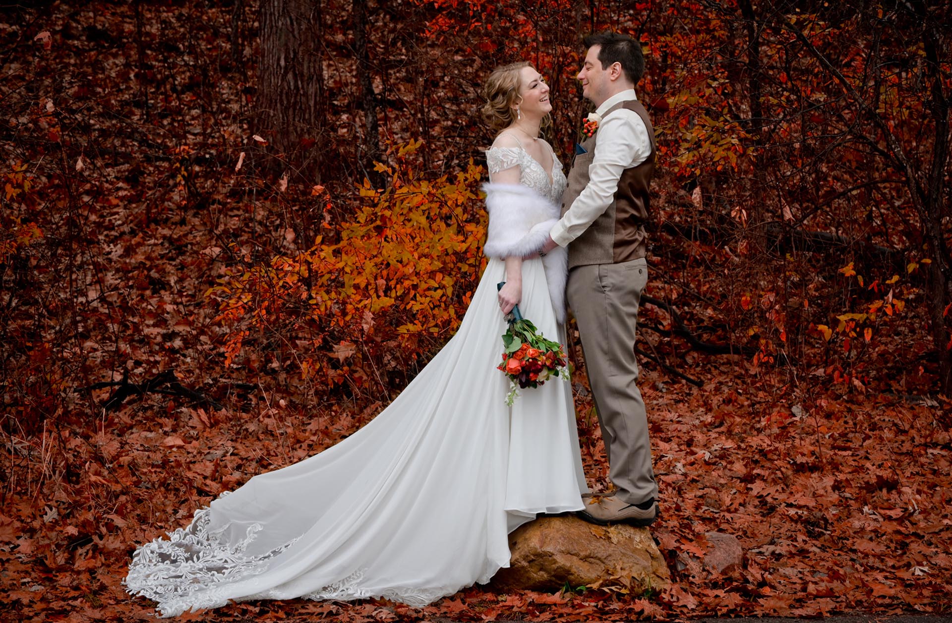 Bride and groom pose in the fall at Waldenwoods Resort in Howell, Michigan surrounded by leaves.