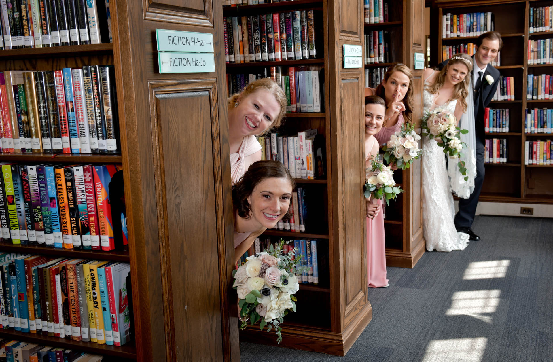 Bride's bridal party pose at the Baldwin Library in Birmingham, Michigan as one of the bridesmaid shushed the photographer.