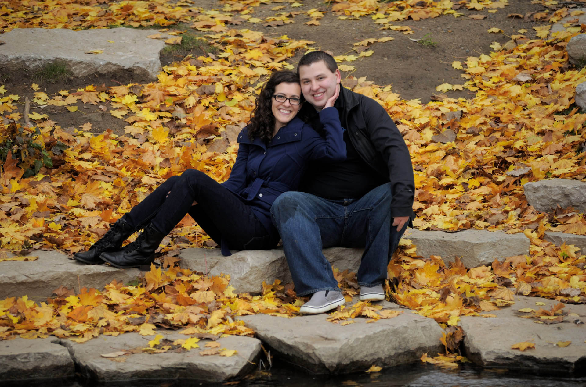 Best Rochester newly engaged couple sit along the leafy shore for this romantic pose in the Rochester, Michigan area.